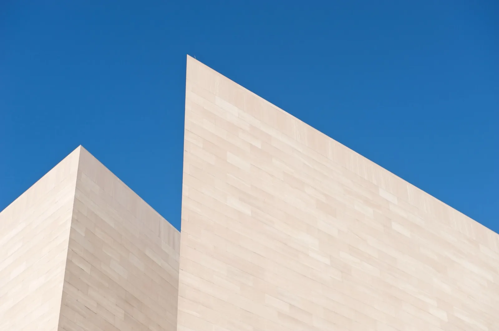 Stone angles of the National Gallery of Art's East Building against a blue sky.
